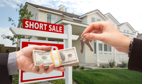 Short Sale sign in front of home with hand exchanging cash for keys