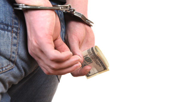 Man in handcuffs holding money in his hand